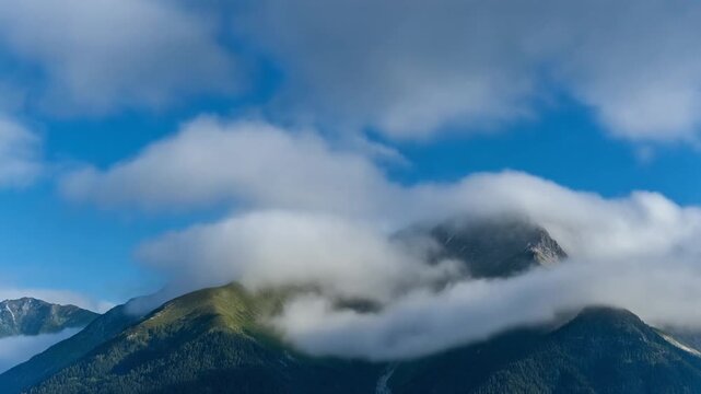 Majestic Mountain Peak Shrouded in Soft Clouds Under a Blue Sky
