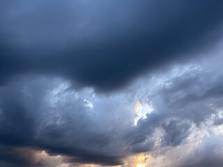 Obraz premium Dark storm clouds heavy sky background with patch of blue sky, dramatic thunderstorm cumulus cloudscape look like eye or heart, hope in crisis and conceptual breakthrough abstract nature wallpaper. 