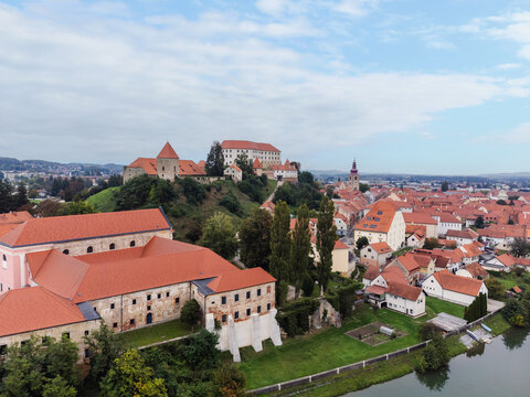 Aerial view of Ptuj, Slovenia, featuring the city center, red-roofed buildings, and the Drava River along with Ptuj Castle.