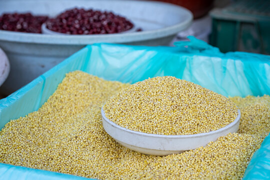 Yellow foxtail millet jo grain piled in a white bowl at local traditional market stall in South Korea.