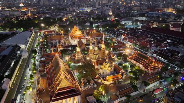Bangkok, Thailand: Aerial night view of Wat Pho Thai Buddhist temple complex (Temple of the Reclining Buddha) in heart of Thai capital city, Grand Palace on horizon - landscape drone panorama