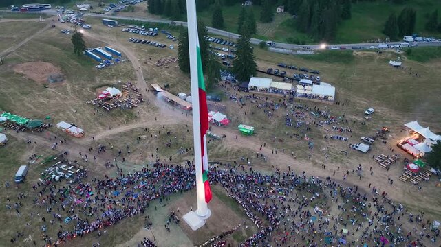 Drone View of Raising the largest and tallest Bulgarian flag on the highest pole on Rozhen Peak in the Rhodope Mountains, near Pamporovo resort, Bulgaria.