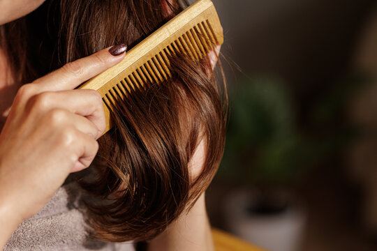Woman Combing Shiny Hair With Wooden Comb At Home