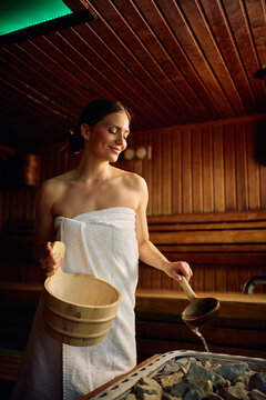Smiling woman during hot stone sauna treatment in luxury wellness center