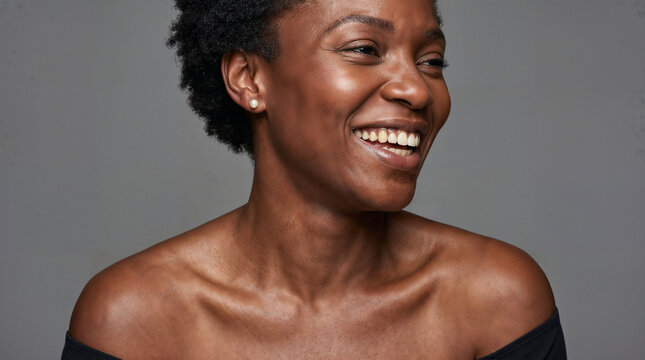 Joyful smiling black woman with natural beauty in studio portrait, confident cheerful expression, healthy skin and positive lifestyle concept.