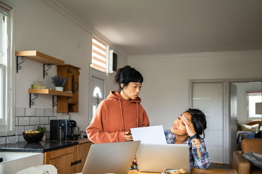 Two women reviewing bills at home kitchen table