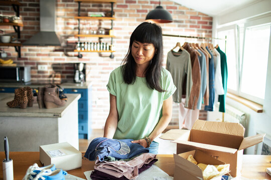 Small business owner packing clothing orders at home