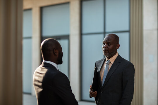 Two businessmen talking in modern office lobby