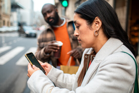 Woman using smartphone for directions on city street
