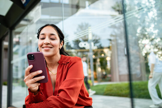 Smiling woman using smartphone outdoors in city