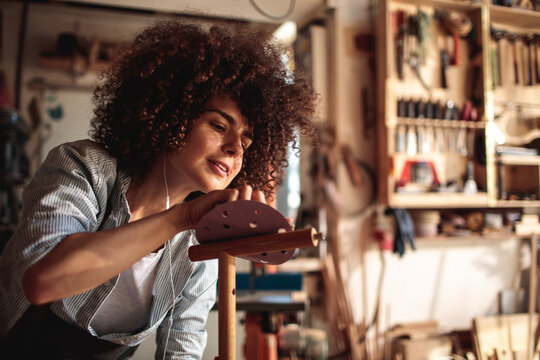 Young craftswoman sanding wood in workshop