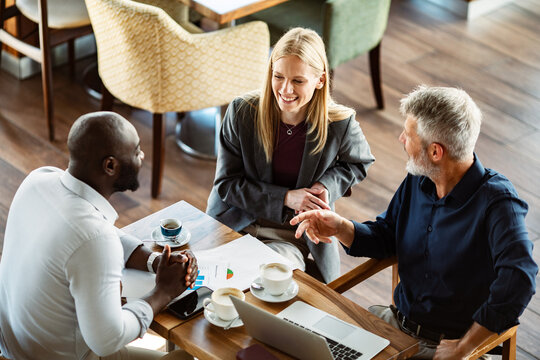 Three business professionals meeting with laptop at coffee shop
