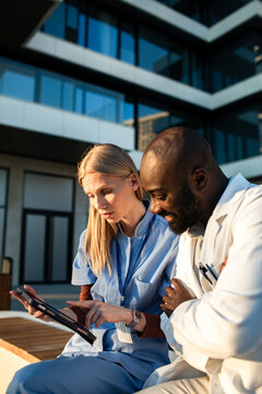 Healthcare professionals collaborating on tablet outside hospital