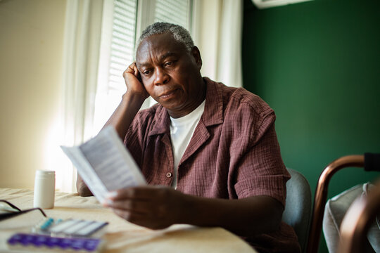 Senior man reading medication instructions at home