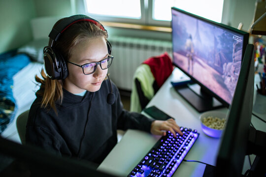 Teen girl playing video game at home desk