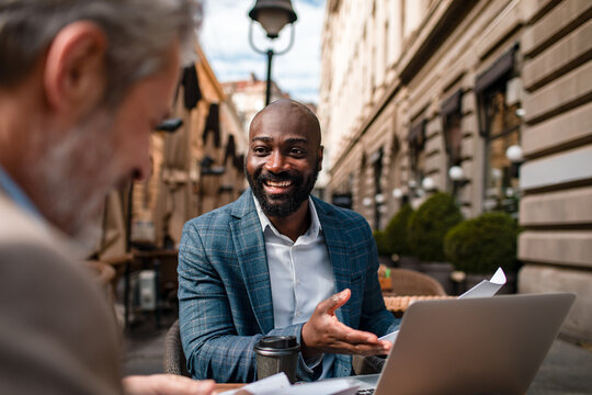Smiling businessman meeting client at outdoor cafe