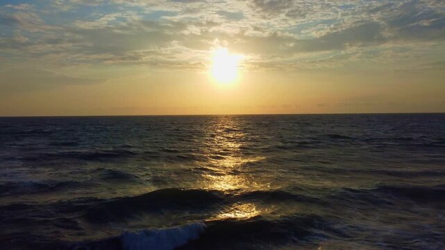 Atardecer esc&eacute;nico en el oc&eacute;ano con luz dorada reflej&aacute;ndose sobre las olas suaves. El sol se posa bajo en el horizonte