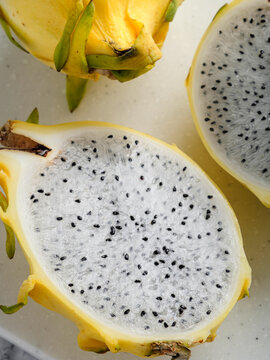 Yellow dragon fruit halves on white speckled cutting board