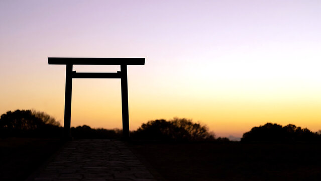 夕日に照らされた簡素な鳥居と奥へ続く石畳の参道