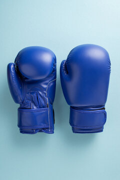 Blue boxing gloves on pastel vertical background representing men's health and blue ribbon awareness month