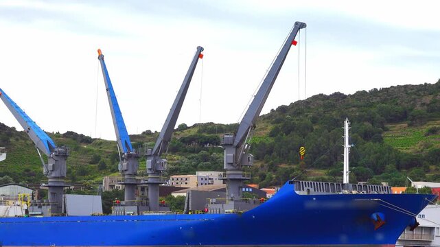 Cranes operate on a cargo ship at the dock