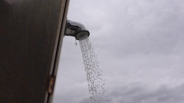 Water flows from a beach showerhead on an overcast day.