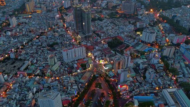 High-angle aerial hyperlapse of busy traffic around Nguyen Trai or Phu Dong roundabout in District 1, Ho Chi Minh City, Vietnam, during dusk with colorful city lights.