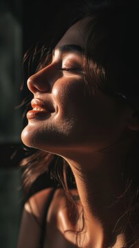 Side-lit portrait of a woman, shadows accentuating a bright white smile, dramatic contrast