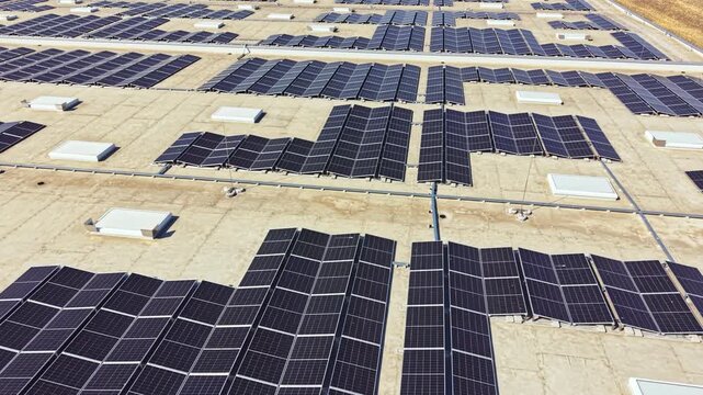 Several solar panels are installed on a flat roof in a sunny area. The panels are placed in rows and sections for maximum energy collection during midday.
