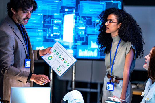 South Asian male and Black female professionals celebrate achievements in a dark tech office holding a certificate of recognition.