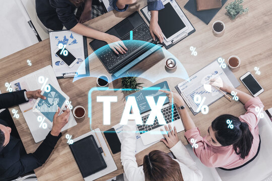 Diverse group engaged in tax preparations with laptops and documents, showcasing collaboration and analysis in financial planning process. Sentient.