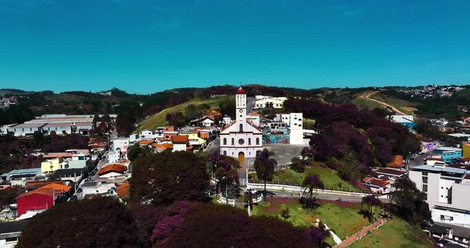 4K aerial drone view of a historic Catholic church surrounded by traditional houses and urban architecture in Santa Isabel, S&atilde;o Paulo, Brazil.