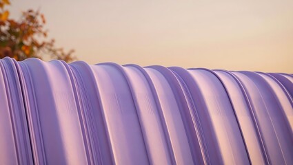 Fototapeta premium A close up of a curved purple metal corrugated surface against a soft golden sky