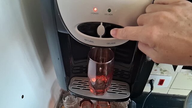 Finger pressing water dispenser button for refreshing motion video footage