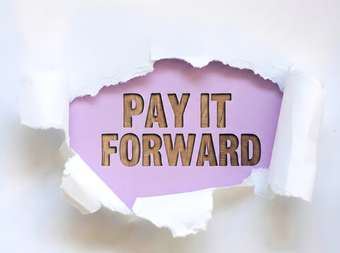 Pay It Forward Message Revealed Through Torn Paper With Wooden Typography On A Soft Purple Background Symbolizing Kindness Generosity And Positive Action