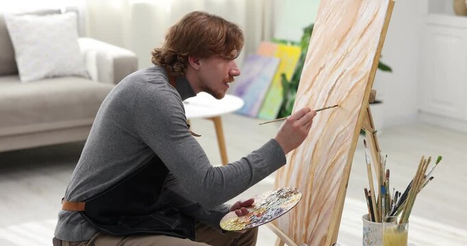 Man painting picture on easel in artist's studio