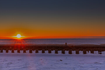 Fototapeta premium Winter sunrise over a frozen pier and Lake Erie at Port Dover, Ontario, Canada.