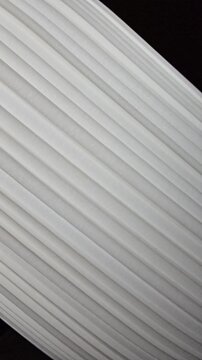 Close-up abstract texture of white pleated fabric or modern blinds, featuring diagonal parallel lines and minimalist geometric patterns.
