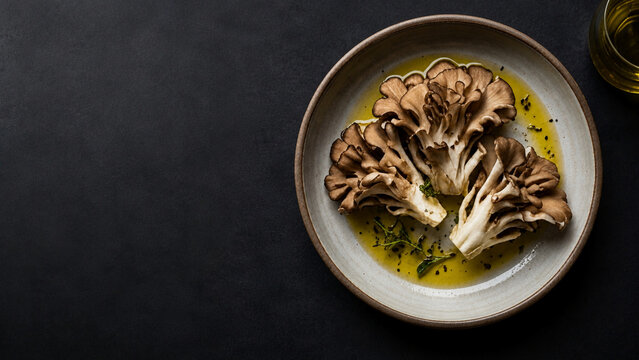 Fresh maitake mushrooms served in olive oil on a ceramic plate