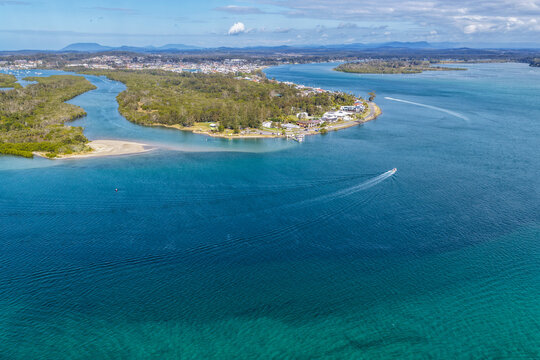 Aerial view from Settlement Point looking along the Hastings River towards Port Macquarie, showcasing the broad waterway, foreshore, surrounding coastal landscape and urban area in the distance