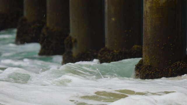white wash waves moving over the barnacles on the pier