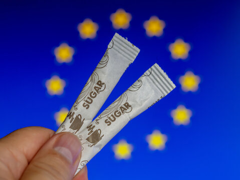 Sugar Packets Held Against European Flag Background