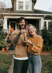 Fototapeta premium Tattooed young couple celebrating home ownership in front of a modern house