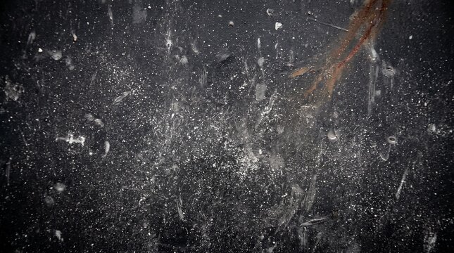 Splashes and droplets of water hitting a dark, textured surface, creating a dynamic and abstract pattern