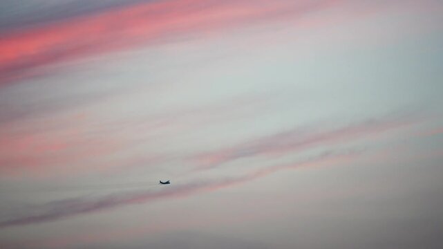 silhouette of airplane fly over red cloud glow and blue sky background, 4k real time footage travel concept