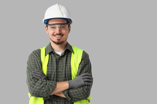 Construction worker safety and professional service, young man in hard hat and reflective vest with arms crossed