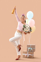 Fototapeta premium Celebration and party concept happy young woman with champagne flowers balloons and gifts on a peach background