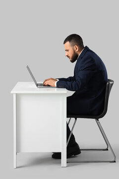 Poor posture and back pain from prolonged computer work, man with bad ergonomics at office desk using laptop