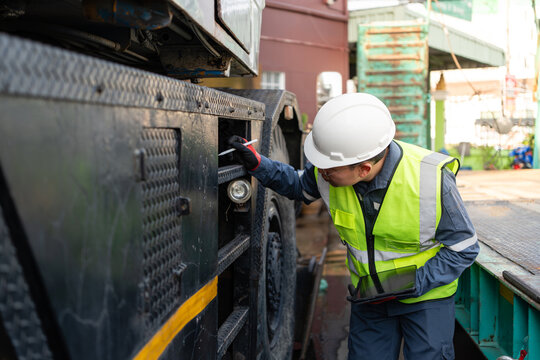 Crane chassis lifting operations safety inspection continues while a male engineer wearing one hard hat holds his digital tablet