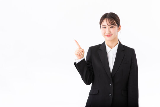 指をさす若いスーツの女性
